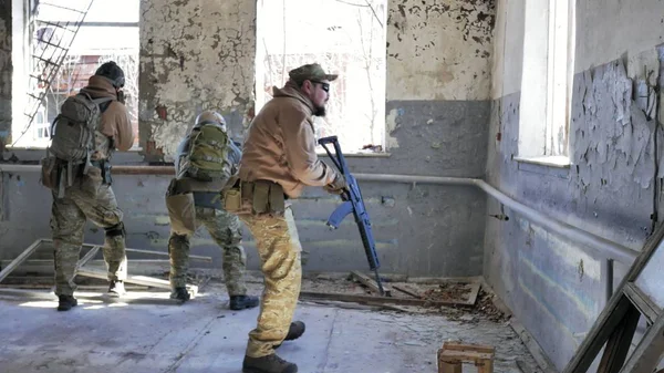 Soldiers in camouflage with a military weapon aiming through the rifle sight through the window of an old building, the military concept — Stock Photo, Image