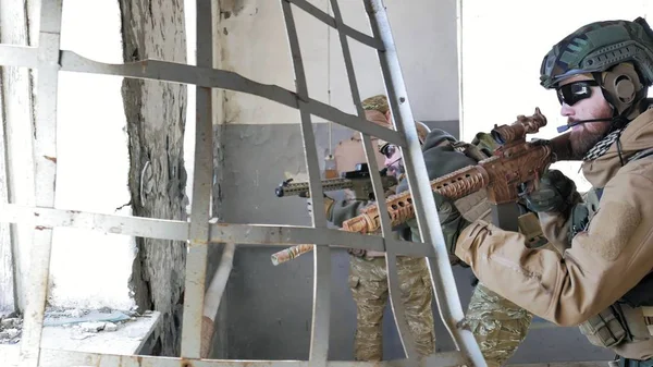 Soldaten in Tarnung mit einer Militärwaffe, die durch das Fenster eines alten Gebäudes auf das Gewehr zielte, das militärische Konzept — Stockfoto