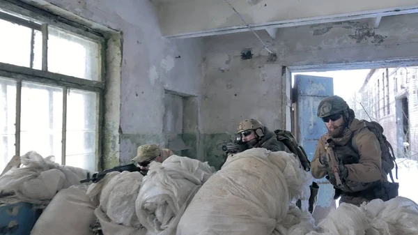 Soldados en camuflaje con armas de combate están siendo disparados en el refugio del viejo edificio, el concepto militar — Foto de Stock