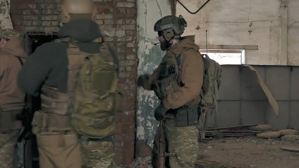 Soldiers in camouflage with combat weapons sneak along the corridors of the old building, the military concept — Stock Photo, Image