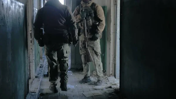 Soldiers in camouflage with combat weapons sneak along the corridors of the old building, the military concept — Stock Photo, Image