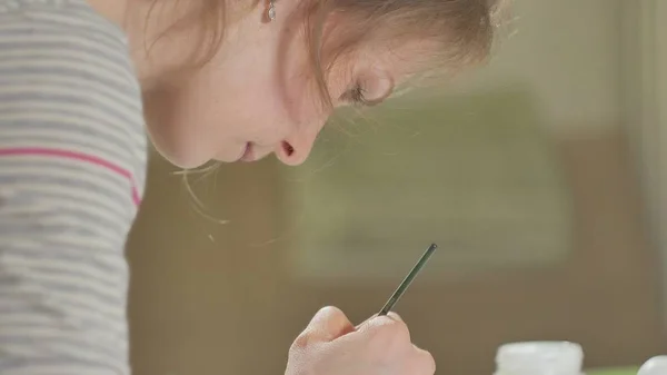 Женщина рисует деревянную куклу цветными красками в своей домашней студии, живопись Матрешки — стоковое фото