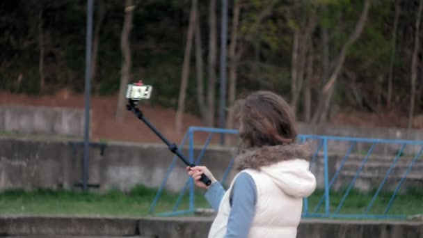 Güzel kız gülümseme almak kendi kendine resim selfie akıllı telefon ile mobil bulunan Parkı — Stok video