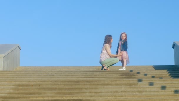 Мати і дочка гуляють у сонячному місті — стокове відео