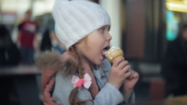 Niedliches Kleinkind Mädchen mit weißer Strickmütze Eis essen — Stockvideo