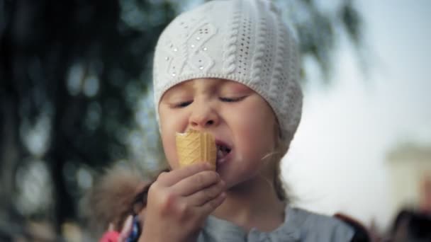 Cute toddler girl in white knitted hat eating ice cream — Stock Video