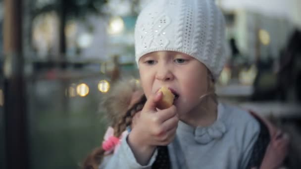 Schattige kleuter meisje in witte gebreide muts eten van ijs — Stockvideo