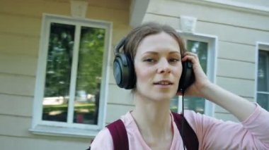 genç şık güzel kadın, şehir sokaklarda büyük monitör kulaklık müzik dinlemek.