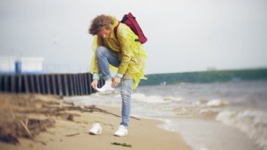 Sahil boyunca seyahat yaşam tarzı macera tatil açık havada yürüyen mutlu kadın. Bir moda sarı yağmurluk giymiş bir kız