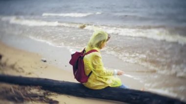 Sahil boyunca seyahat yaşam tarzı macera tatil açık havada yürüyen mutlu kadın. Bir moda sarı yağmurluk giymiş bir kız