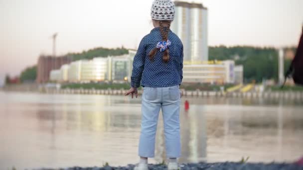 Niña lanzando una piedra al agua — Vídeos de Stock