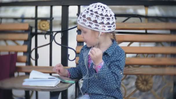 Little stylish beautiful gerl, on city streets listening to music in l headphones. — Stock Video