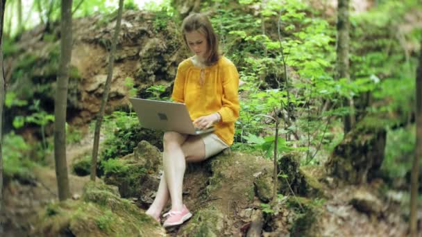 Ragazza con computer portatile, Seduto su una roccia, Nella foresta — Video Stock