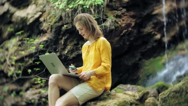 Flicka med Laptop, sitter på en sten, i skogen — Stockvideo