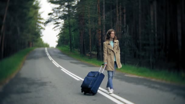 海の碑文を持つテーブルでスーツケースを道路上に若い美しい女性ヒッチハイク立って — ストック動画