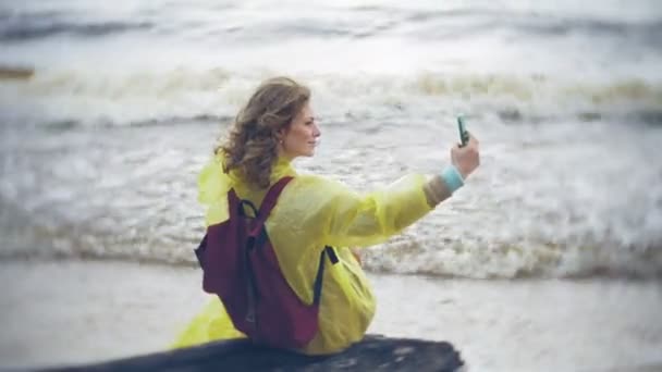 Mujer feliz caminando por la costa Viajando Estilo de vida aventura vacaciones al aire libre. Una chica vestida con un impermeable amarillo de moda — Vídeo de stock