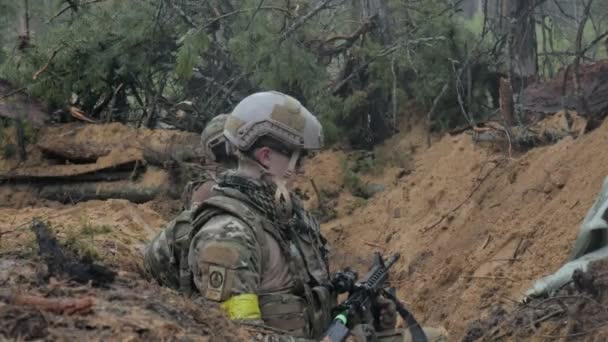 Soldados en camuflaje con armas de combate están siendo disparados en el refugio del bosque, el concepto militar — Vídeo de stock