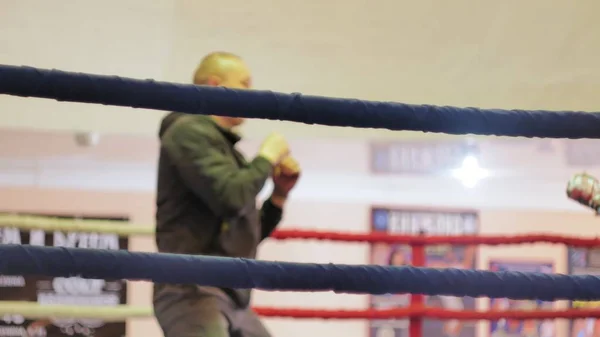 El entrenador lleva a cabo una batalla de entrenamiento con una kickboxer femenina en el ring —  Fotos de Stock