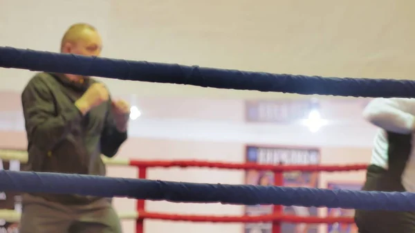 Der Trainer führt einen Trainingskampf mit einer Kickboxerin im Ring — Stockfoto