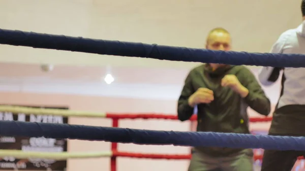 El entrenador lleva a cabo una batalla de entrenamiento con una kickboxer femenina en el ring —  Fotos de Stock