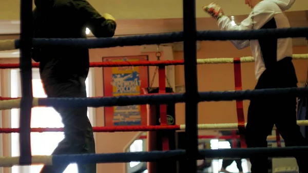 Tränare bedriver en träning strid med en kvinnlig kickboxare i ringen — Stockfoto