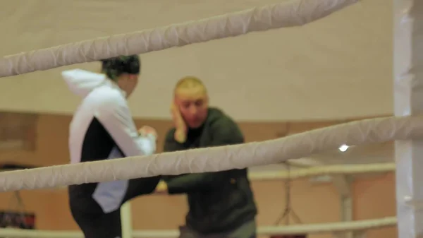 Der Trainer führt einen Trainingskampf mit einer Kickboxerin im Ring — Stockfoto