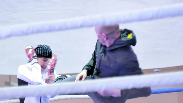 El entrenador lleva a cabo una batalla de entrenamiento con una kickboxer femenina en el ring —  Fotos de Stock