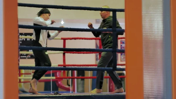 De trainer voert een strijd van de opleiding met een vrouwelijke kickboxer in de ring — Stockfoto