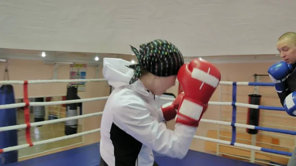 De trainer voert een strijd van de opleiding met een vrouwelijke kickboxer in de ring — Stockfoto