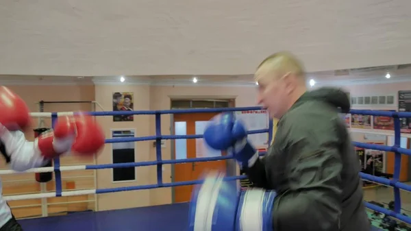 Tränare bedriver en träning strid med en kvinnlig kickboxare i ringen — Stockfoto