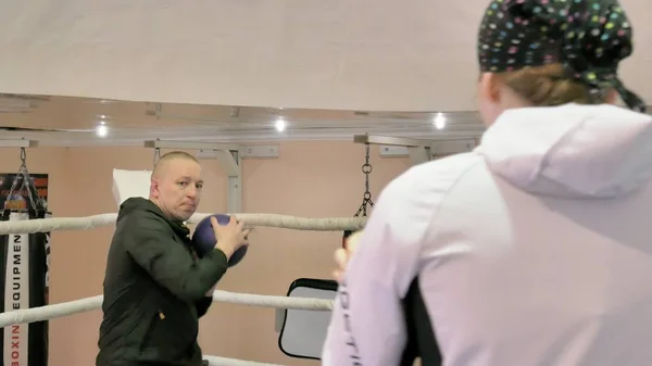Der Trainer im Training wirft einen schweren Ball mit einer Kickboxerin in den Ring — Stockfoto