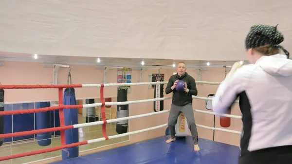 Trener w szkoleniu rzuca piłkę ciężki z kobiece kickboxer w pierścieniu — Zdjęcie stockowe