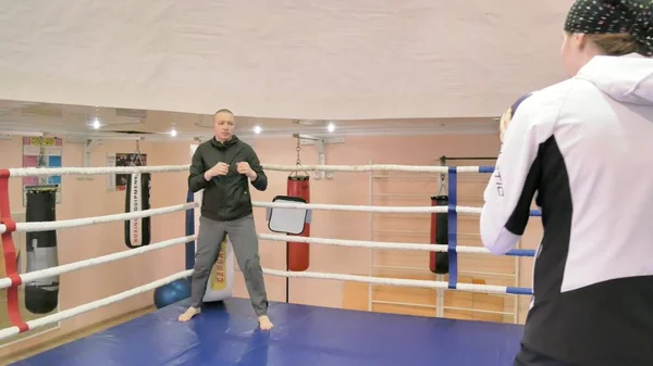 Trener w szkoleniu rzuca piłkę ciężki z kobiece kickboxer w pierścieniu — Zdjęcie stockowe