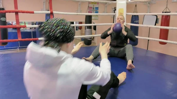 El entrenador en entrenamiento lanza una pelota pesada con una kickboxer femenina en el ring — Foto de Stock