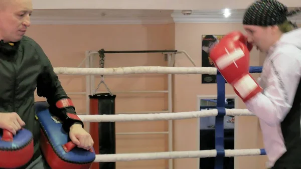 Der Trainer führt einen Trainingskampf mit Pfoten mit einer Kickboxerin im Ring — Stockfoto