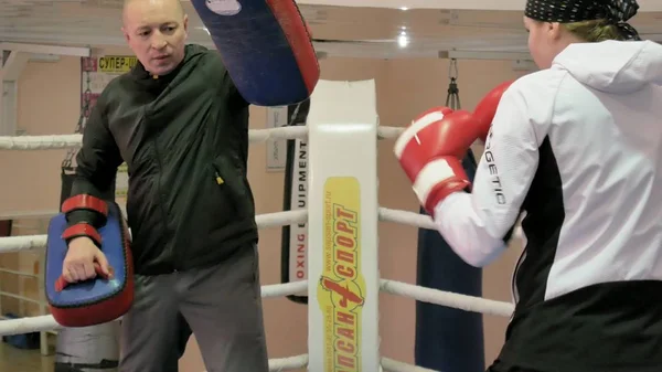 El entrenador lleva a cabo una batalla de entrenamiento con las patas con una kickboxer femenina en el ring —  Fotos de Stock