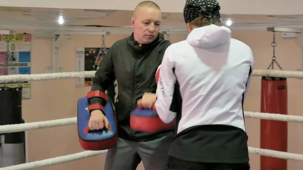 El entrenador lleva a cabo una batalla de entrenamiento con las patas con una kickboxer femenina en el ring — Foto de Stock