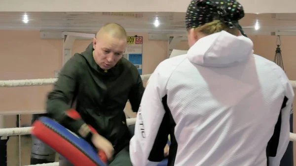 L'entraîneur mène une bataille d'entraînement avec des pattes avec une femme kickboxer dans le ring — Photo