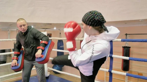 Der Trainer führt einen Trainingskampf mit Pfoten mit einer Kickboxerin im Ring — Stockfoto