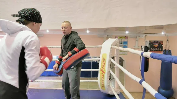 El entrenador lleva a cabo una batalla de entrenamiento con las patas con una kickboxer femenina en el ring — Foto de Stock