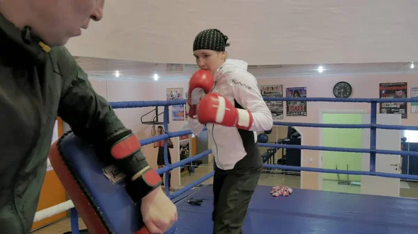 L'allenatore conduce una battaglia di allenamento con le zampe con una kickboxer donna sul ring — Foto Stock