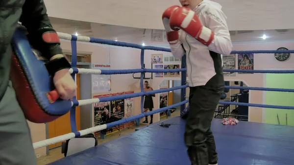 Der Trainer führt einen Trainingskampf mit Pfoten mit einer Kickboxerin im Ring — Stockfoto