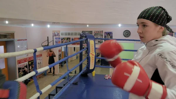 El entrenador lleva a cabo una batalla de entrenamiento con las patas con una kickboxer femenina en el ring —  Fotos de Stock