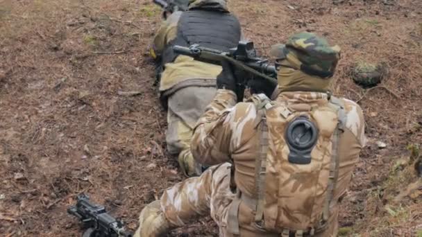 Soldados em camuflagem com armas de combate estão sendo disparados no abrigo da floresta, o conceito militar — Vídeo de Stock