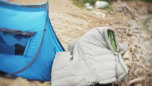 강둑에 관광 텐트입니다. 여자는 텐트 근처 앉아서 강 보인다. — 비디오