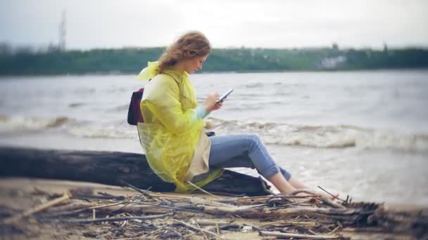 Lycklig kvinna promenader längs kusten reser livsstil äventyr semester utomhus. En flicka klädd i en fashionabel gul regnrock — Stockvideo