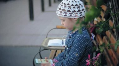 Bir telefon ile büyüleyici bir kız parkta elini kolunu sallaya dönüyor ve fotoğraf çeker