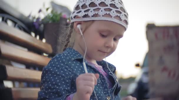 Little stylish beautiful gerl, on city streets listening to music in l headphones. — Stock Video