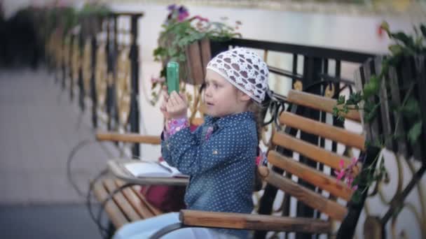 Bir telefon ile büyüleyici bir kız parkta elini kolunu sallaya dönüyor ve fotoğraf çeker — Stok video