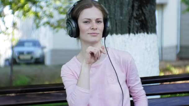 Joven mujer hermosa con estilo, en las calles de la ciudad escuchando música en los auriculares del monitor grande . — Vídeos de Stock